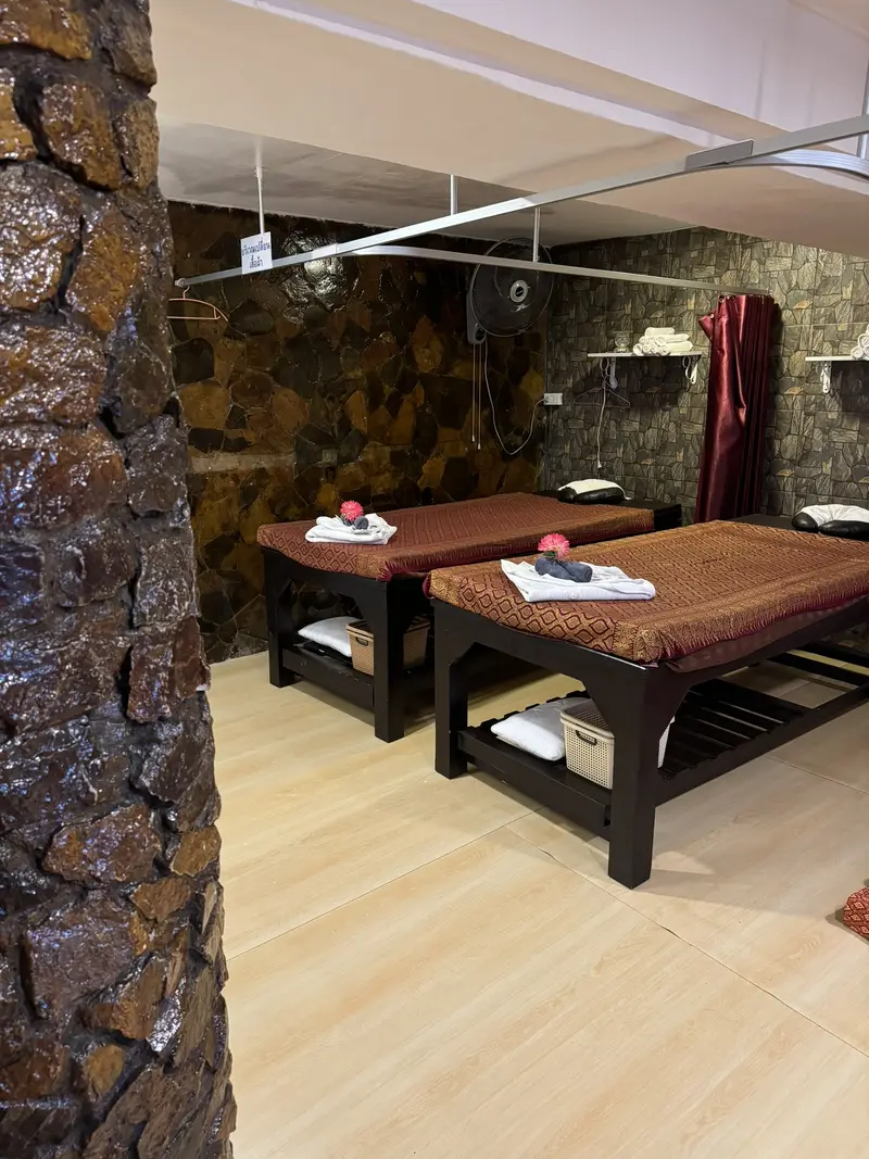 Treatment room with two massage beds, folded towels and a stone feature wall